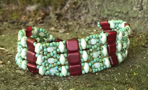 This lovely and intricately beaded Brocade bracelet measures approximately 7" and closes with a magnetic clasp. Glass beads include Czech Fire-polished crystals, Czech glass tiles and Superduos and glass seed beads in green turquoise, seafoam green and claret.