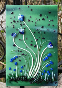 Sultry Creamy White Vitrigraph stems topped with serene torch work Bluebells begin to emerge in your garden for an early Spring! The background flaunts distant purple blooms. This little garden fused glass art panel scene measures 5” x 8”. 