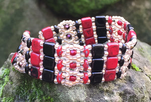 This lovely and intricately beaded Brocade bracelet of Red, Black and matte gold measures approximately 6 1/4" and closes with a magnetic clasp. Glass beads include Czech Fire-polished crystals, Czech glass tile, Superduos and glass seed beads. Another option: matching additional thinner bracelet for $20 more.