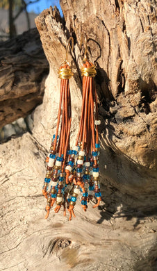Free flowing medium brown leather cords with deep blue, cream, brown and gold seed beads, these Cattail Style Leather Earrings measure approximately 3 1/2