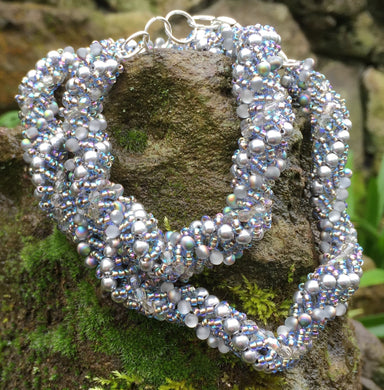This gorgeous vine like necklace is woven with Swarovski and Czech glass beads and pearls in silver, matte clear, and Crystal AB, for that hint of iridescent color. It is adjustable and can be worn between 17 1/2